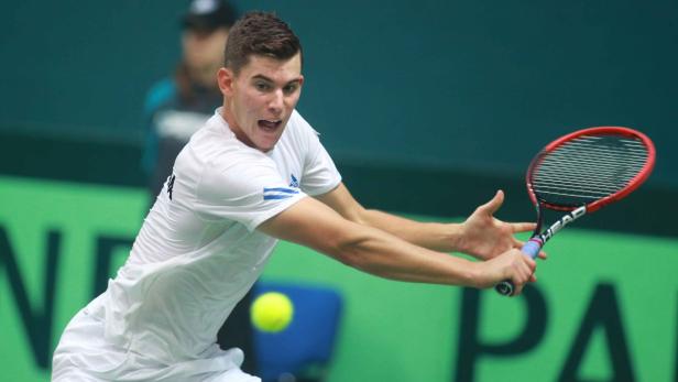 Ein Tennisspieler schlägt einen gelben Ball mit seinem Schläger.
