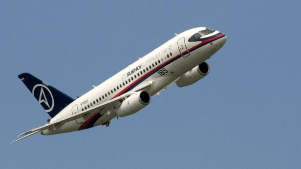 Ein Sukhoi Superjet 100 steigt vor blauem Himmel auf.