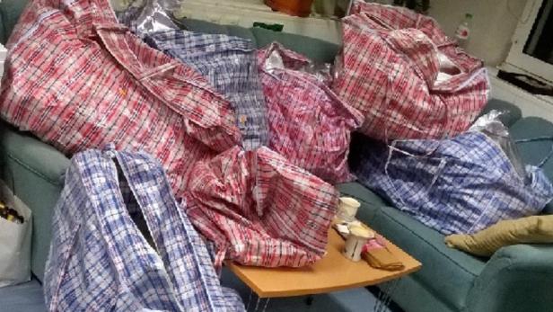 Ein Sofa ist mit mehreren großen, karierten Taschen überladen.