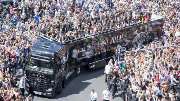 Die deutsche Fußballnationalmannschaft feiert ihren Weltmeistertitel auf einem Truck inmitten einer jubelnden Menschenmenge.