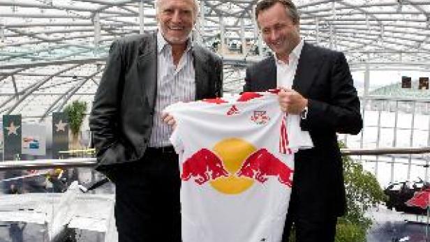 Zwei Männer halten ein Trikot von Red Bull in die Kamera.