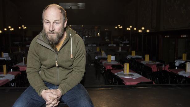 Ein Mann mit Bart sitzt in einem leeren Restaurant oder Theater.