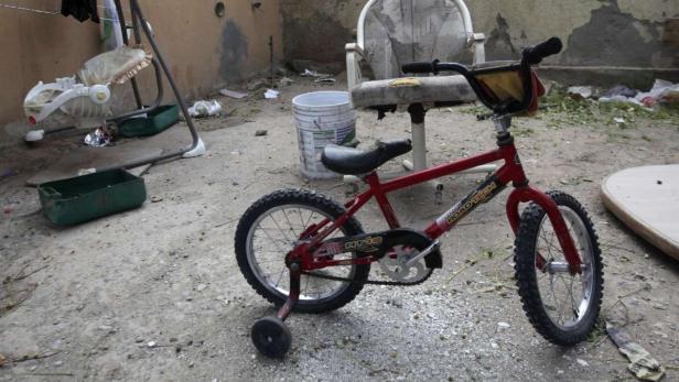 Ein rotes Kinderfahrrad mit Stützrädern steht im Freien.