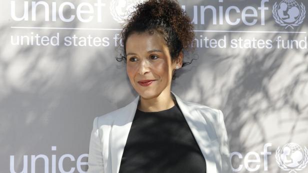 Eine Frau mit lockigem Haar posiert vor einem UNICEF-Hintergrund.