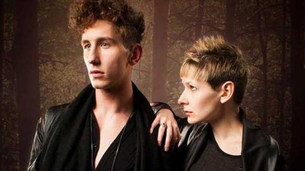 Ein junger Mann und eine Frau posieren vor einem dunklen Waldhintergrund.