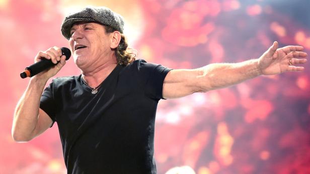 Brian Johnson von AC/DC singt auf der Bühne mit erhobenem Arm.