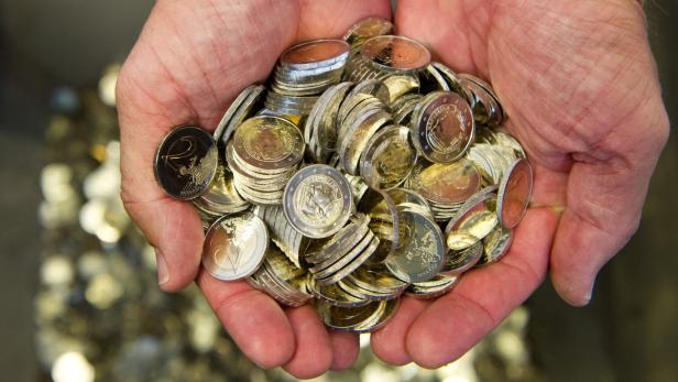 Eine Person hält eine Handvoll Euro-Münzen.
