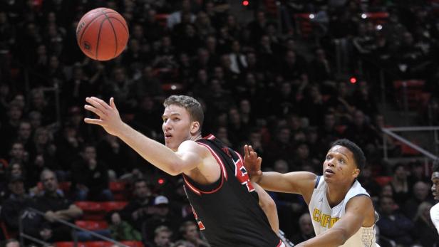 Ein Basketballspieler versucht, einen Ball zu fangen, während ein anderer Spieler ihn beobachtet.