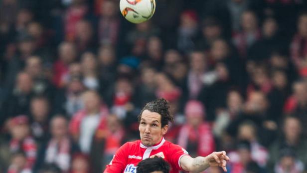 Ein Fußballspieler köpft den Ball vor einer Zuschauermenge.