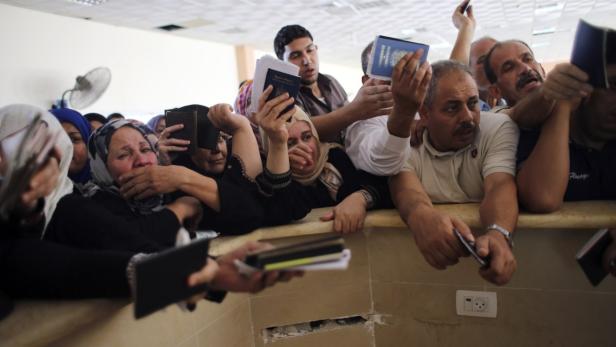 Menschen drängen sich mit Pässen an einem Schalter, einige weinen.
