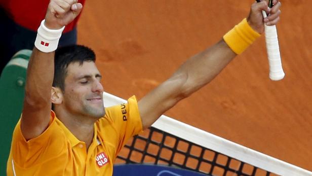 Novak Đoković feiert mit erhobenen Armen einen Tennissieg.