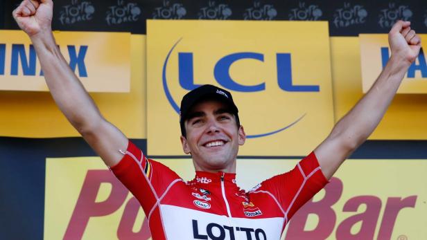 Ein Radrennfahrer im Trikot des Teams Lotto Soudal jubelt mit erhobenen Armen.