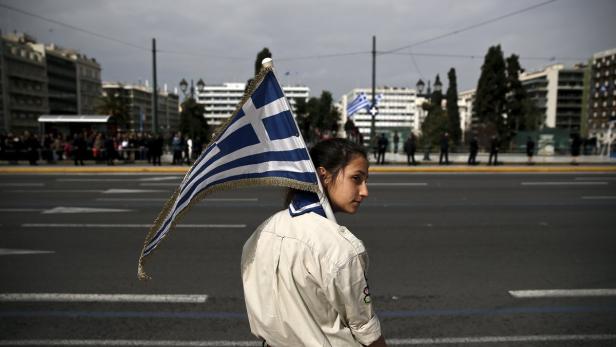 Ein junges Mädchen mit einer griechischen Flagge auf den Schultern bei einer Parade.