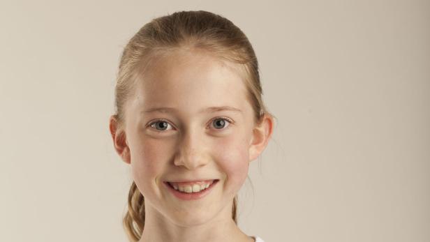 Porträt eines lächelnden jungen Mädchens vor einem hellen Hintergrund.