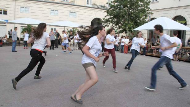 Eine Gruppe junger Leute rennt auf einem Platz um die Wette.