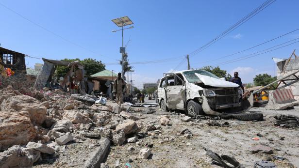 Ein zerstörtes Auto steht auf einer Straße voller Trümmer.