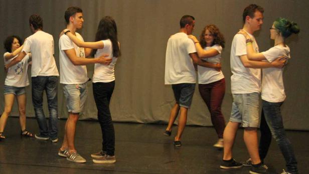 Mehrere Paare tanzen eng umschlungen auf einer Bühne.