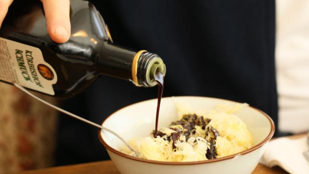 Kürbiskernöl wird in eine Schüssel mit Krautsalat gegossen.