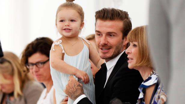 David Beckham hält seine Tochter Harper in den Armen, neben ihm Anna Wintour.