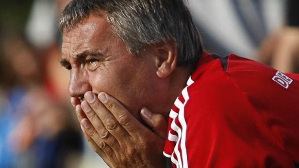 Ein Mann in roter Sportkleidung hält sich mit besorgter Miene die Hände vor das Gesicht.