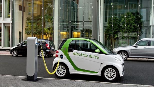 Ein weißer Smart „electric drive“ wird an einer Ladesäule aufgeladen.