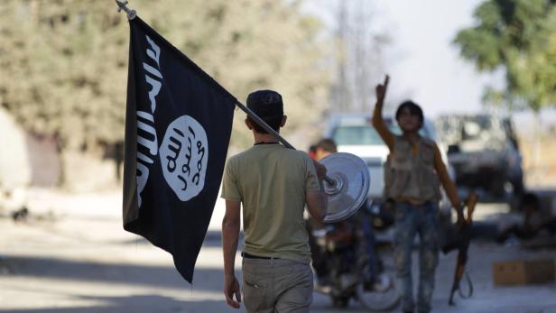 Ein Rebellenkämpfer in Syrien trägt eine zurückgelassene IS-Fahne