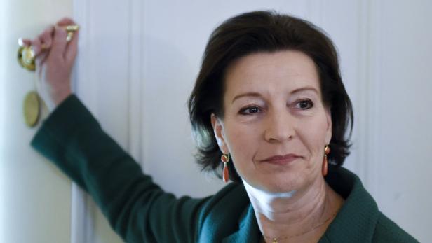 Eine Frau in einer grünen Jacke öffnet eine weiße Tür.