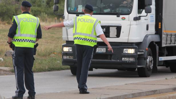 Zwei Polizisten regeln den Verkehr vor einem Lastwagen.
