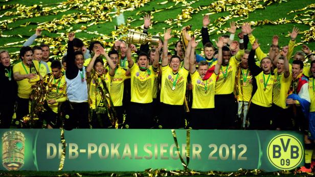 Die Mannschaft von Borussia Dortmund feiert den DFB-Pokalsieg 2012 mit dem Pokal und Konfetti.
