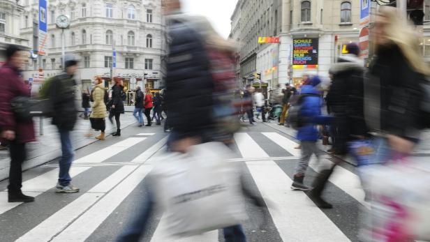 Menschen überqueren einen Zebrastreifen in einer belebten Stadt.