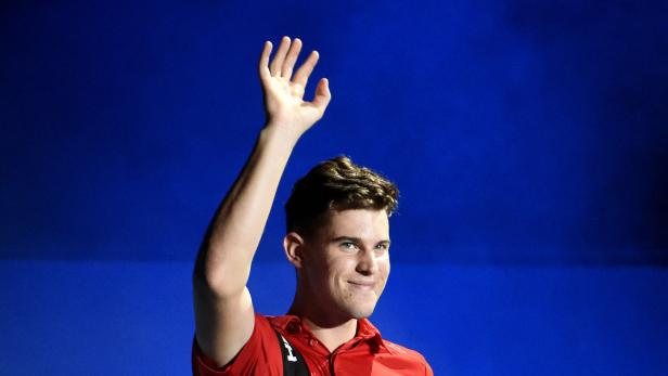 Ein junger Mann in einem roten Hemd winkt vor einem blauen Hintergrund.