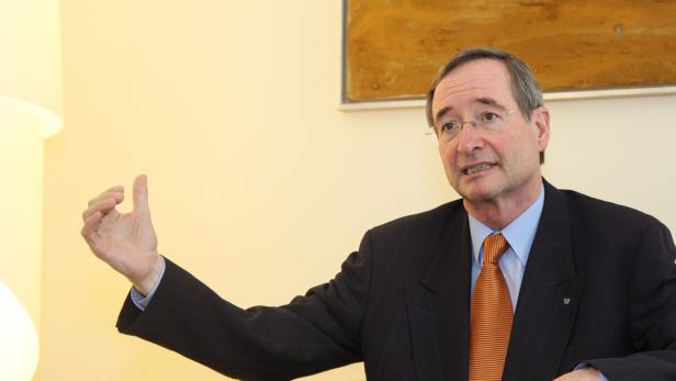 Ein Mann mit Brille, Anzug und Krawatte gestikuliert mit der Hand.