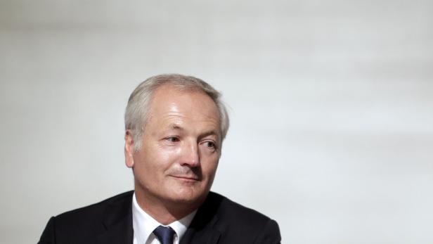 Ein Mann mit grauem Haar und dunklem Anzug blickt zur Seite.
