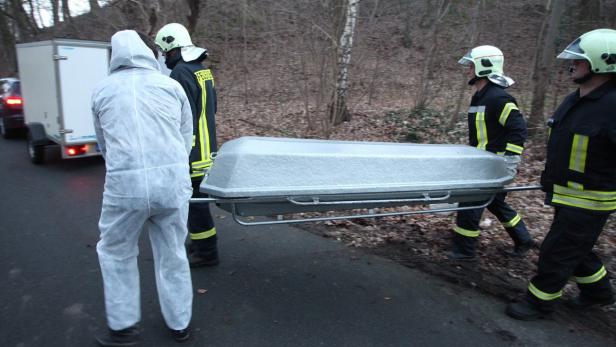 Feuerwehrleute transportieren einen Sarg auf einer Trage.