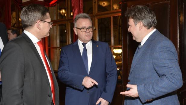 Drei Männer in Anzügen unterhalten sich angeregt.