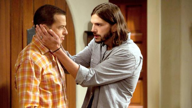 Ashton Kutcher berührt Jon Cryers Gesicht.