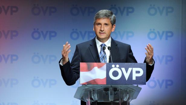 Ein Mann in einem Anzug steht vor einem Rednerpult mit dem ÖVP-Logo.