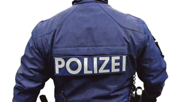 Die Rückansicht eines Polizisten in Uniform mit der Aufschrift „POLIZEI“.