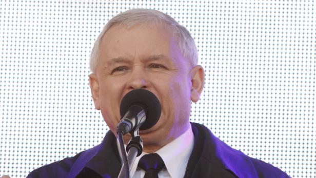 Jarosław Kaczyński spricht in ein Mikrofon vor einem LED-Bildschirm.