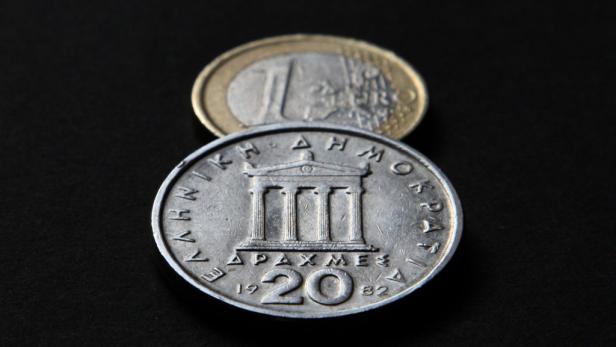 Eine griechische 20-Drachmen-Münze von 1982 liegt vor einer 1-Euro-Münze.