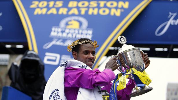 Der Gewinner des Boston-Marathons 2015 mit Lorbeerkranz und Siegerpokal.