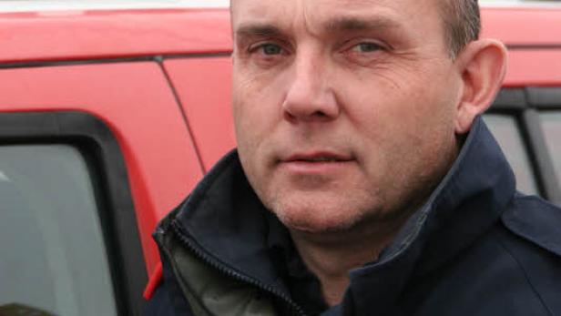 Ein Mann in Uniform steht vor einem roten Fahrzeug mit dem Abzeichen „BFKDO Gänserndorf Schicker“.