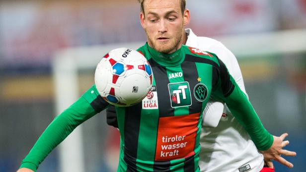 Ein Fußballspieler in Grün-Schwarz kontrolliert den Ball mit der Brust.