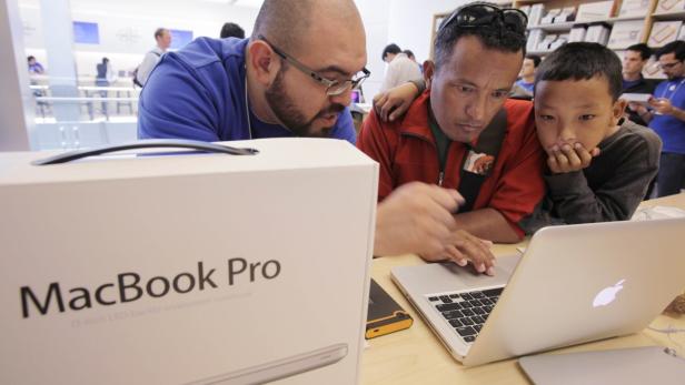 Zwei Männer und ein Kind betrachten einen Laptop in einem Apple Store.