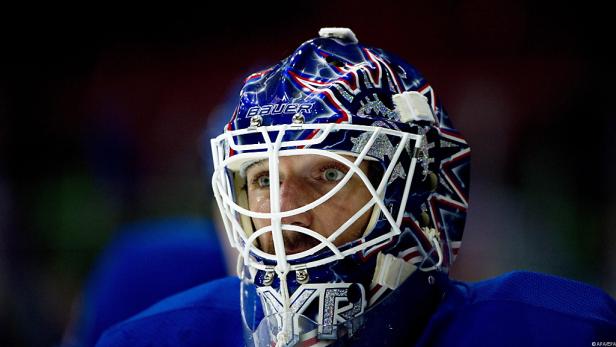 Ein Eishockeytorwart mit einer blau-weiß-roten Maske blickt aufmerksam nach vorne.
