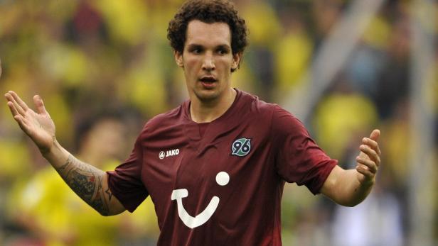 Ein Fußballspieler von Hannover 96 mit Tätowierungen auf dem Arm gestikuliert auf dem Spielfeld.