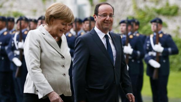 Angela Merkel und François Hollande schreiten vor einer Ehrenformation entlang.