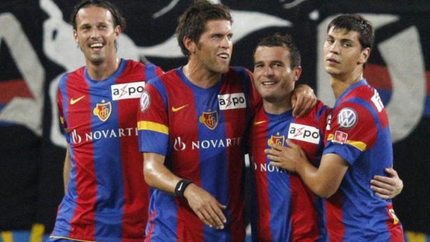 Vier Fußballspieler des FC Basel in rot-blauen Trikots feiern gemeinsam.