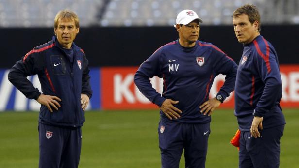 Drei Trainer der US-amerikanischen Fußballnationalmannschaft stehen auf dem Spielfeld.