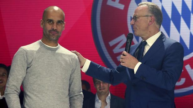 Pep Guardiola wird von einem Mann im Anzug mit einem Mikrofon auf der Bühne begrüßt.